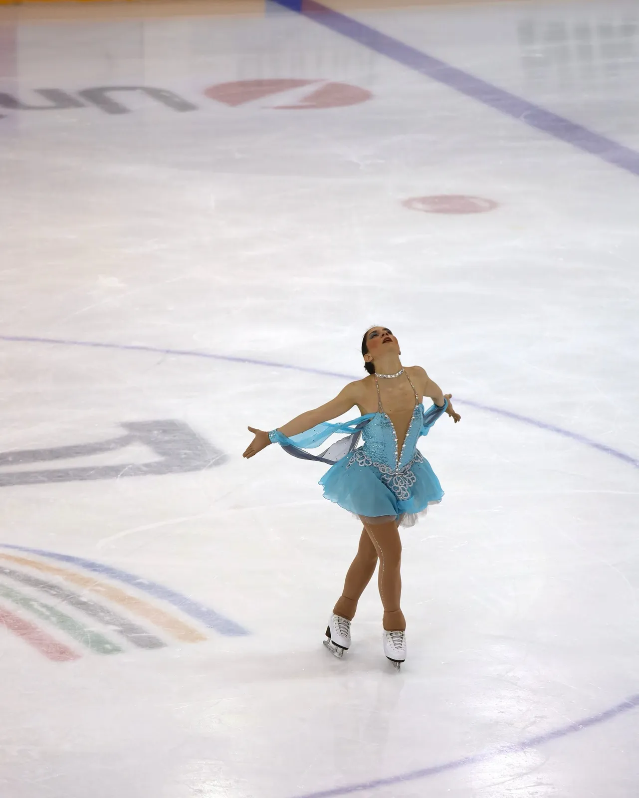 Pattinatrice in abito azzurro durante il programma sul ghiaccio.