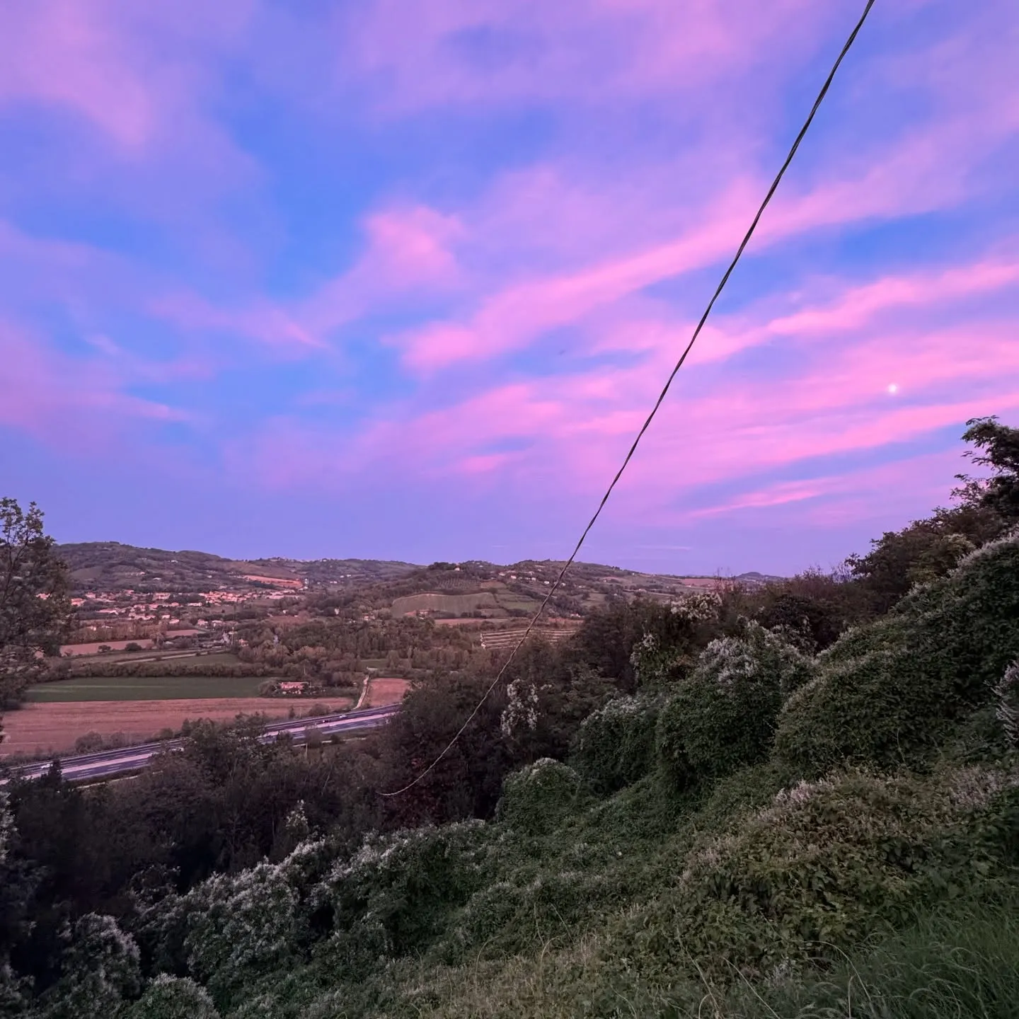 Tramonto magenta sopra colline e campi.