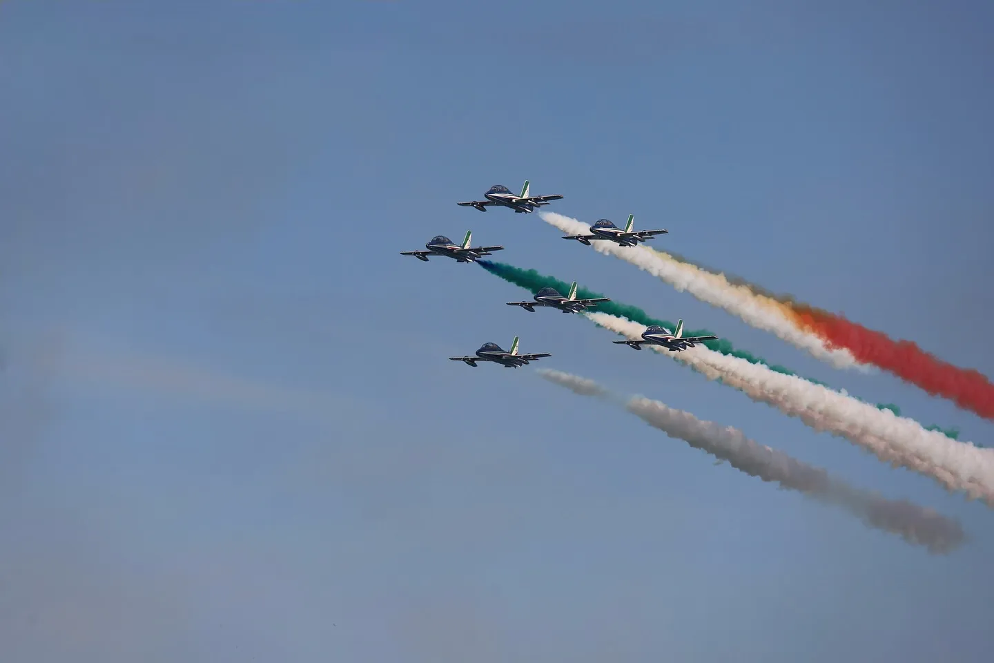 Frecce Tricolori in formazione compatta con scie tricolori.