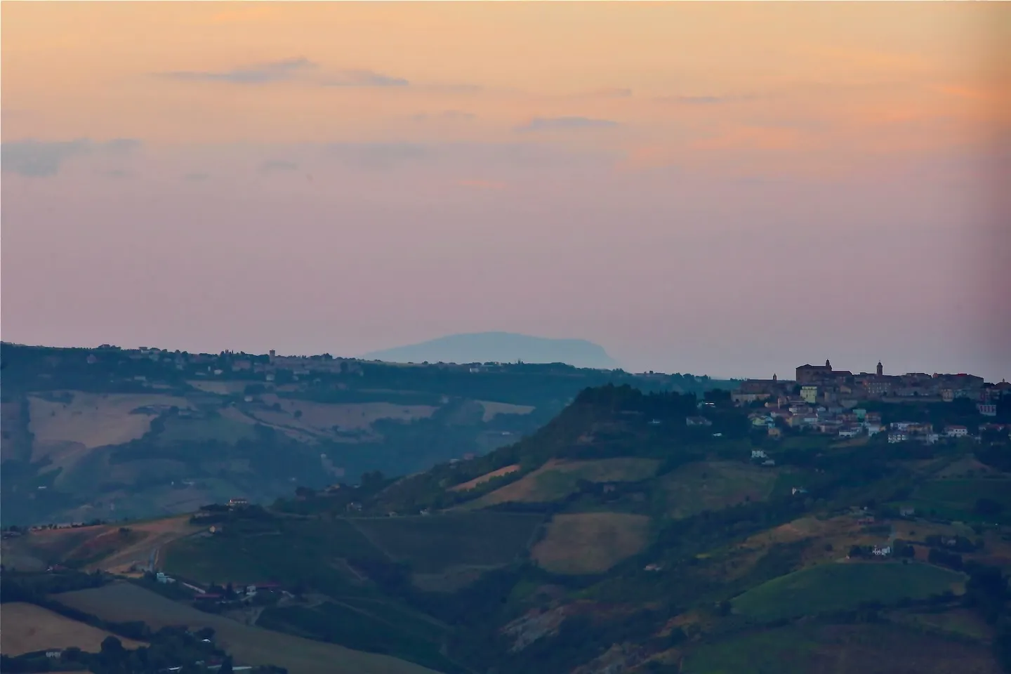 Colline marchigiane al tramonto, con il paesaggio che sfuma verso l'orizzonte.