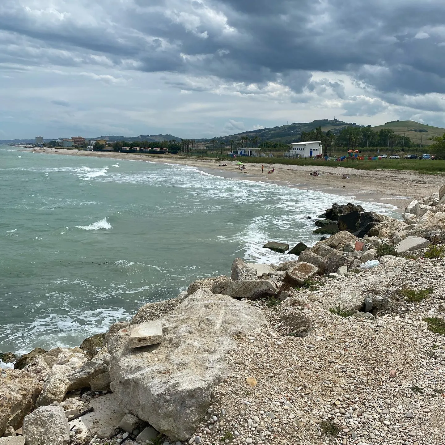 Litorale adriatico osservato dalla scogliera, sotto un cielo carico di nuvole.