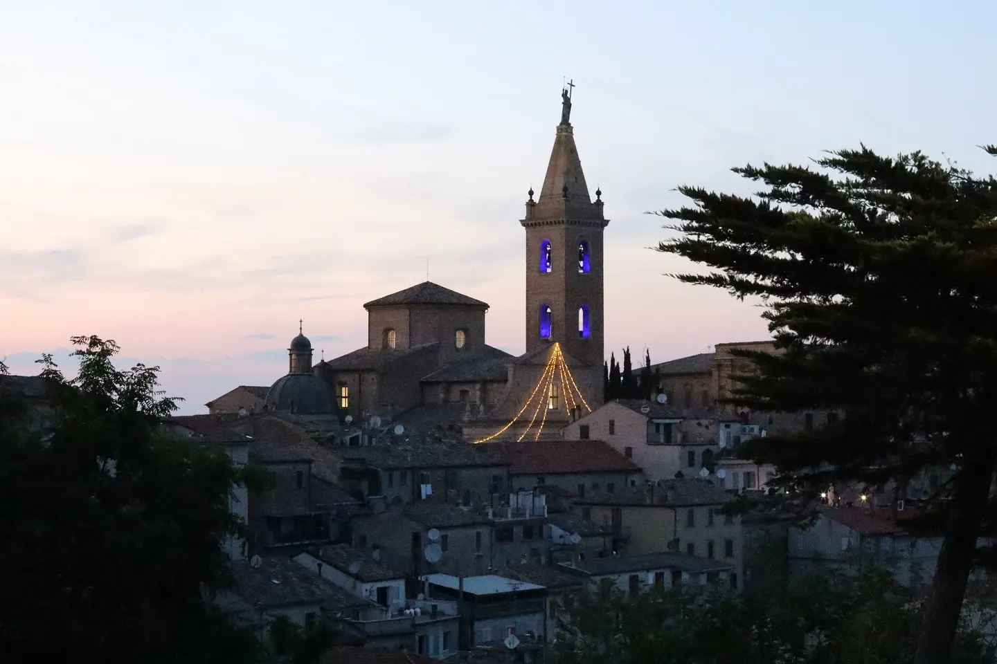 Profilo di un borgo marchigiano al tramonto, con il campanile in evidenza.