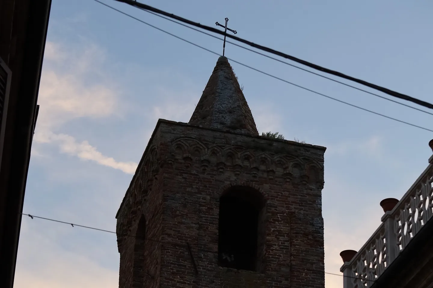 Campanile in mattoni osservato tra i vicoli all'ora blu.