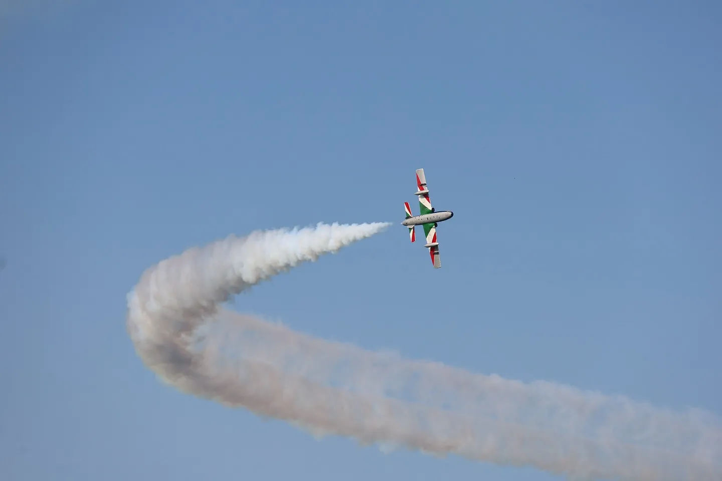 Velivolo acrobatico durante una manovra circolare con scia di fumo.