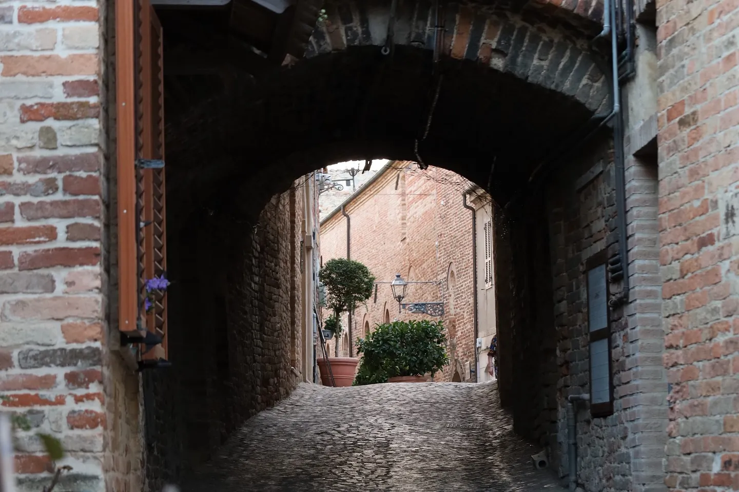 Arco in mattoni e pavimentazione in pietra in un borgo storico.