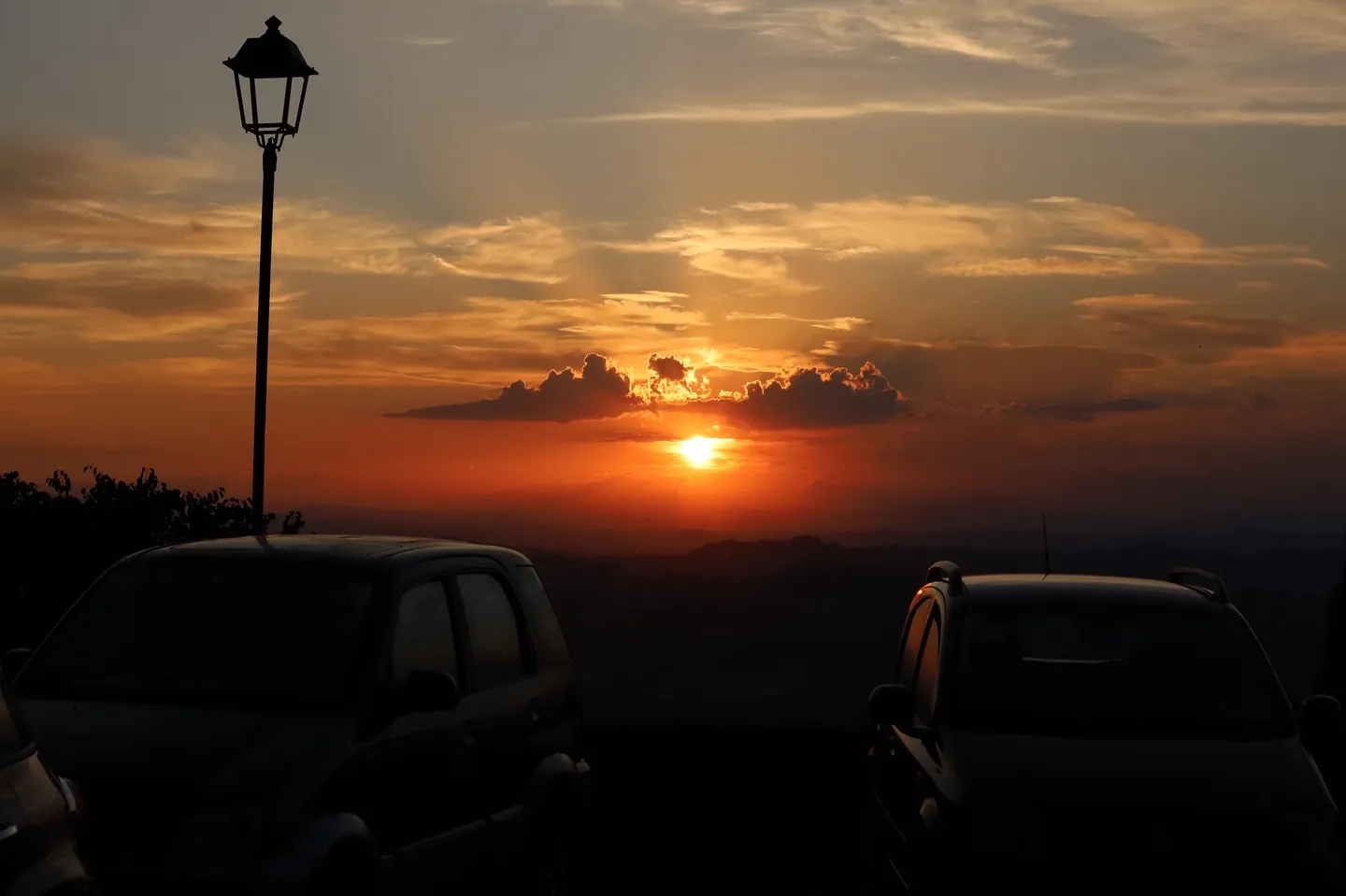 Tramonto sulle colline, con il sole basso tra le nuvole.