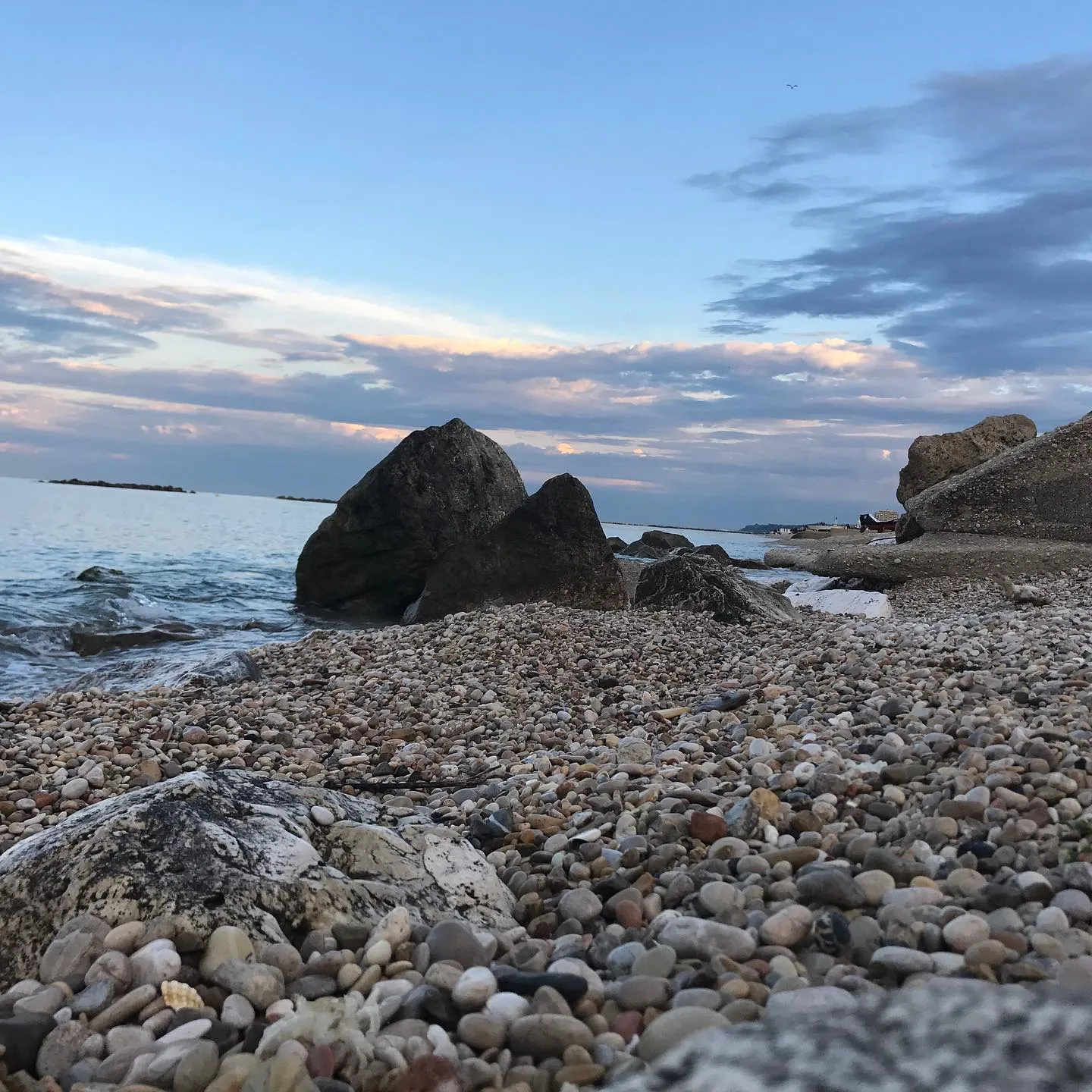 Costa adriatica — spiaggia di ciottoli e grandi scogli al crepuscolo.