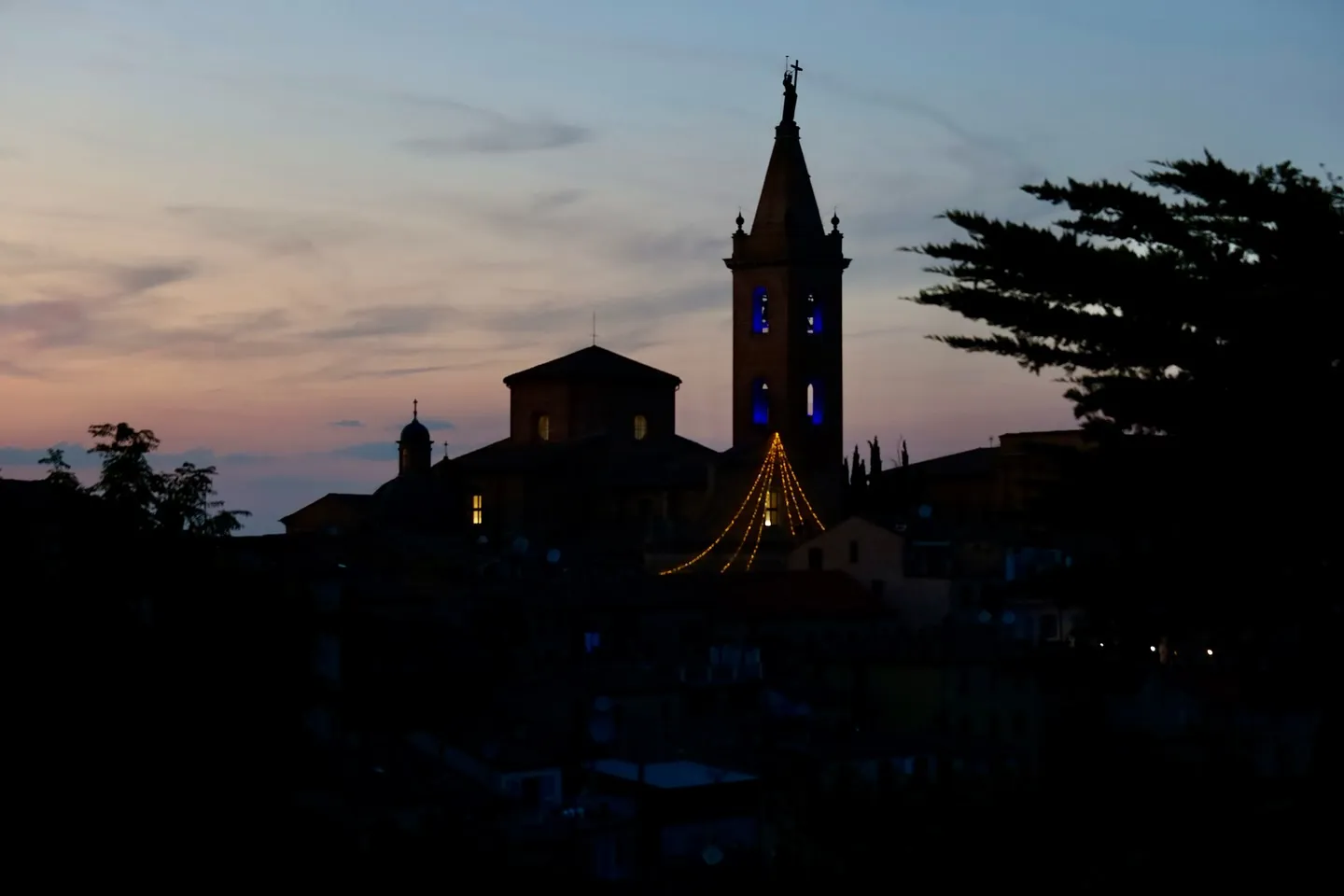 Campanile di un borgo al crepuscolo, con il cielo che conserva l'ultima luce.
