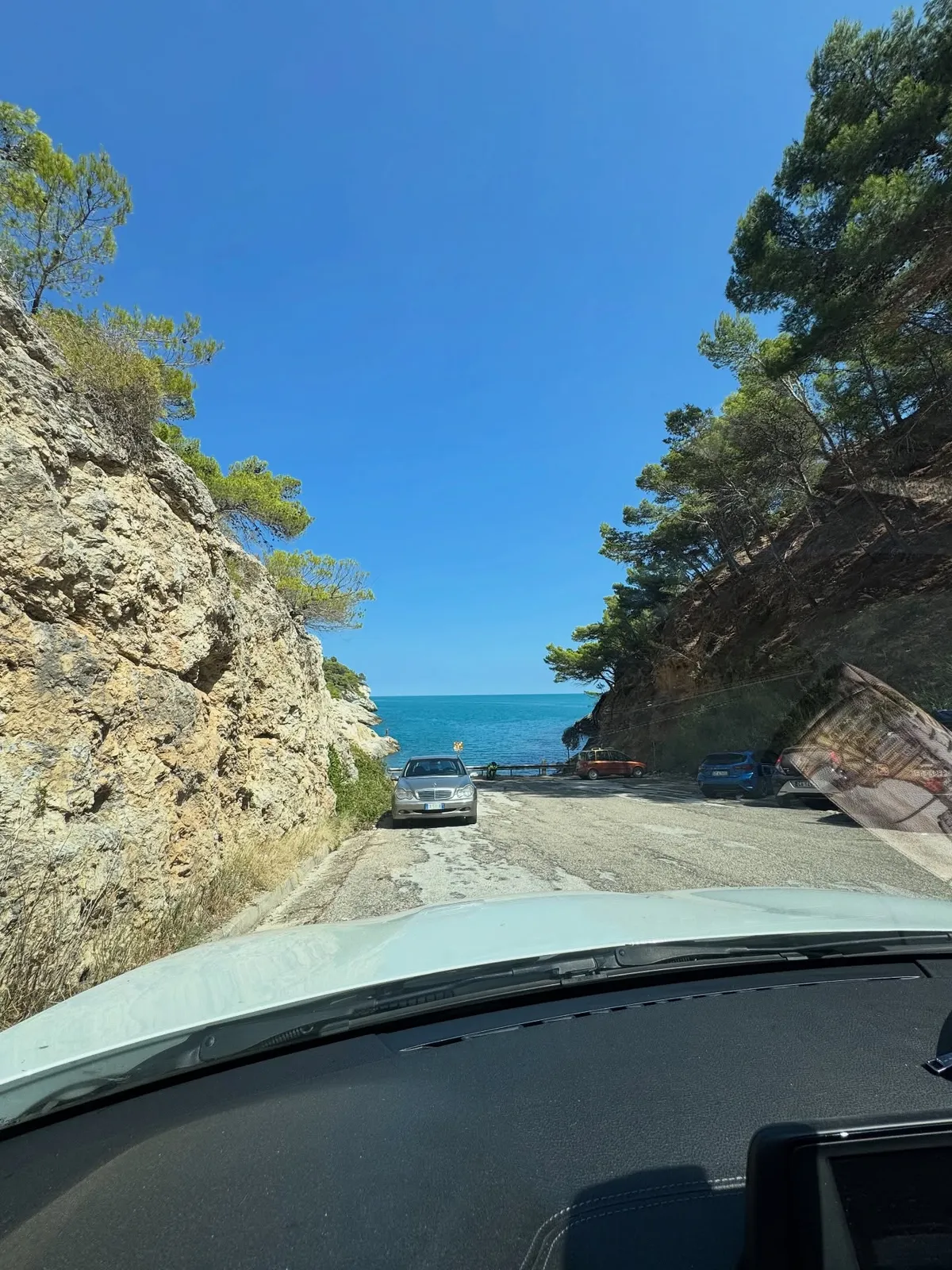 Costa adriatica — strada panoramica tra roccia, vegetazione e mare.