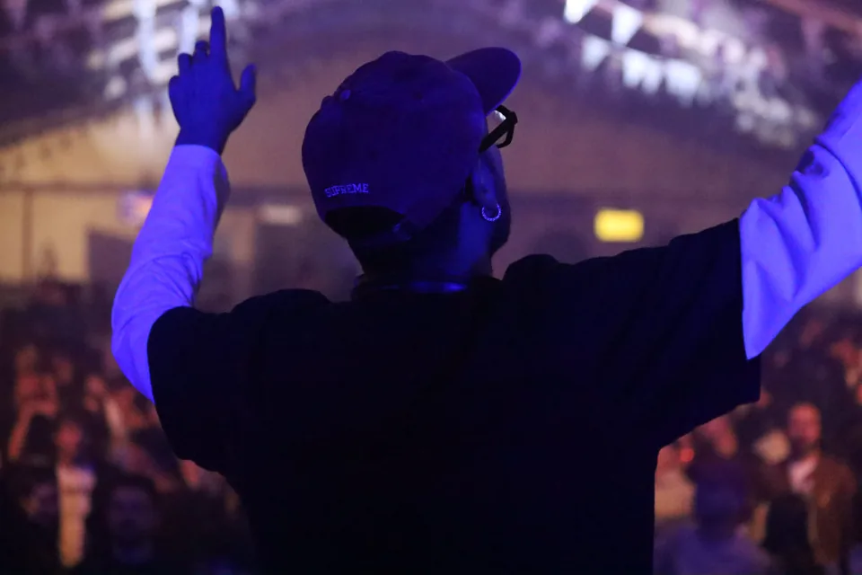 Il DJ alza le braccia davanti alla folla.