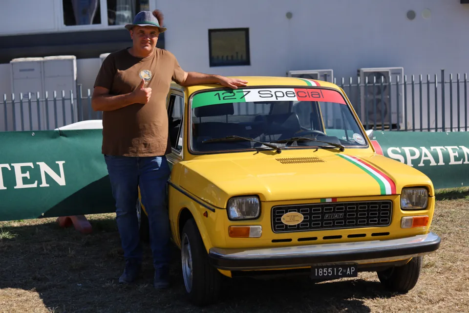 Un partecipante in posa accanto alla sua auto gialla.